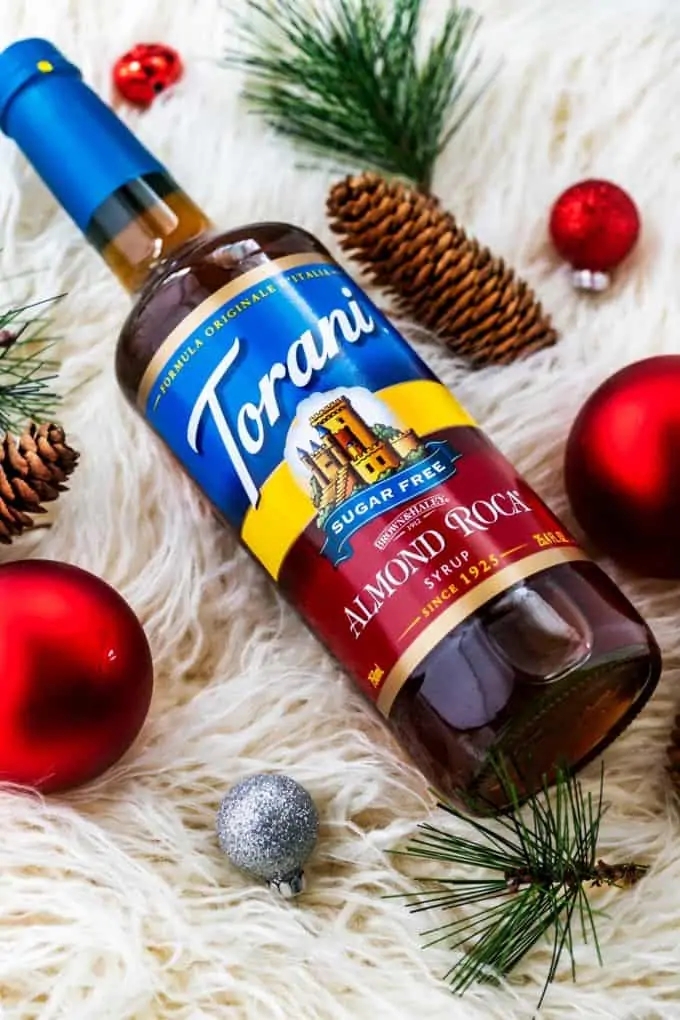 Overheat photo of Torani Sugar Free Almond Roca Syrup surrounded by holiday decorations.