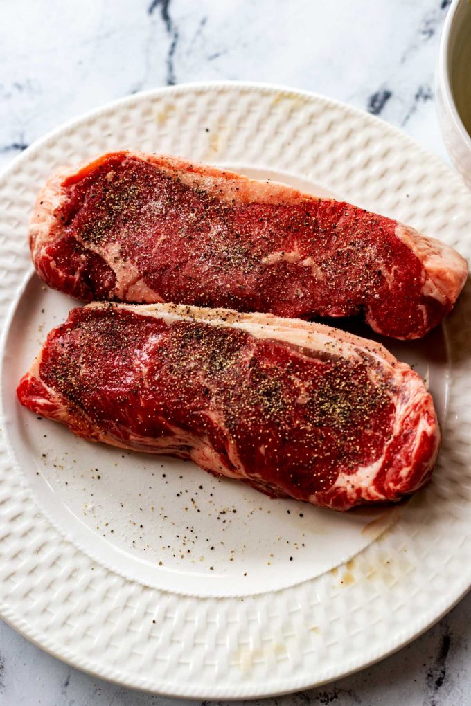 Photo of two seasoned strip steaks.