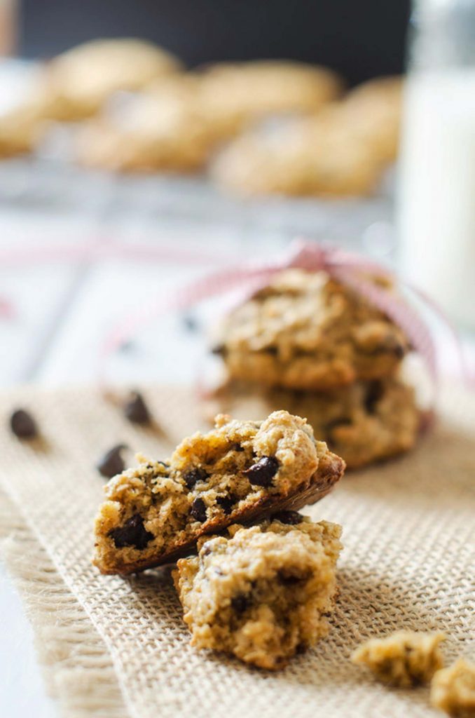 Photo of chocolate chip quinoa cookies on burlap with a stack of cookies behind it tied with a ribbon.