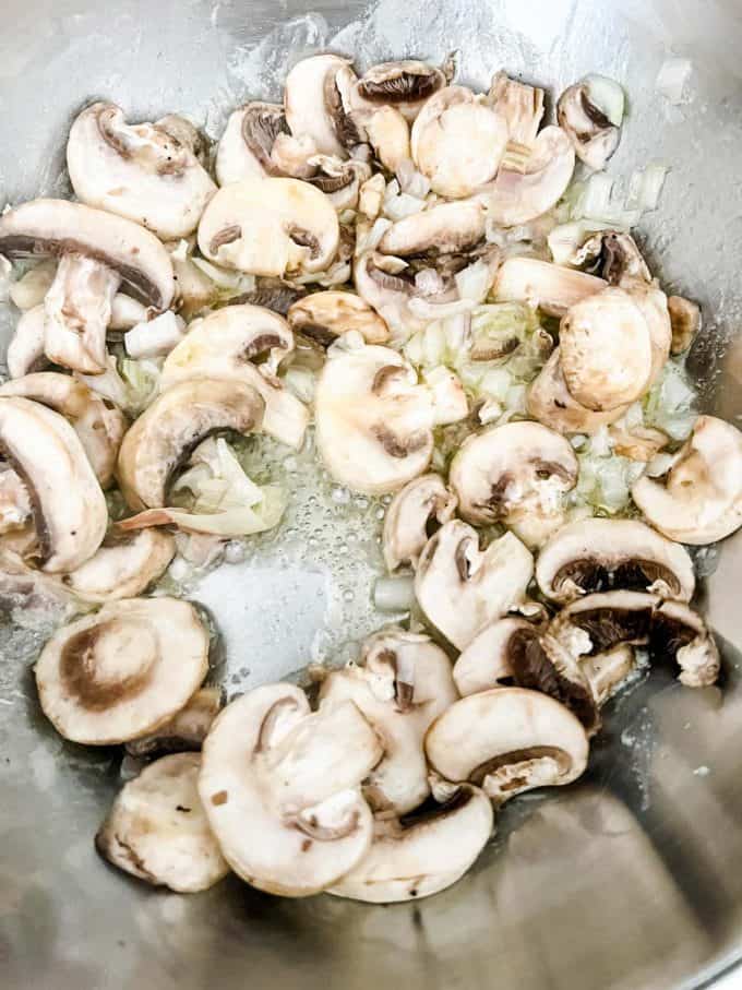 Photo of shallots, garlic, and mushrooms cooking in a saucepan.