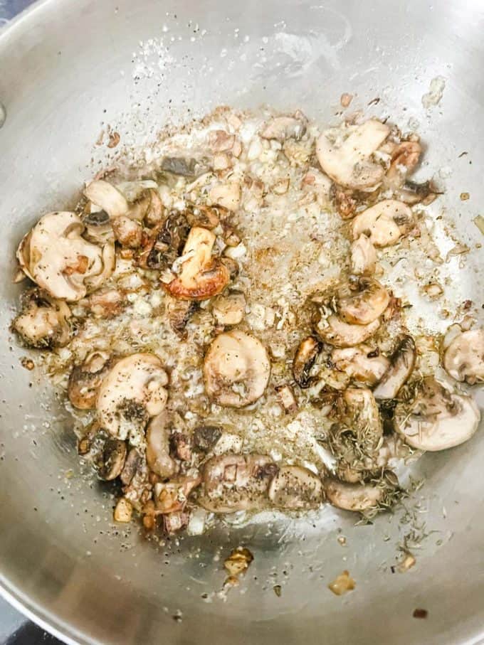 Photo of cooked mushrooms, shallots, and garlic in a saucepan.