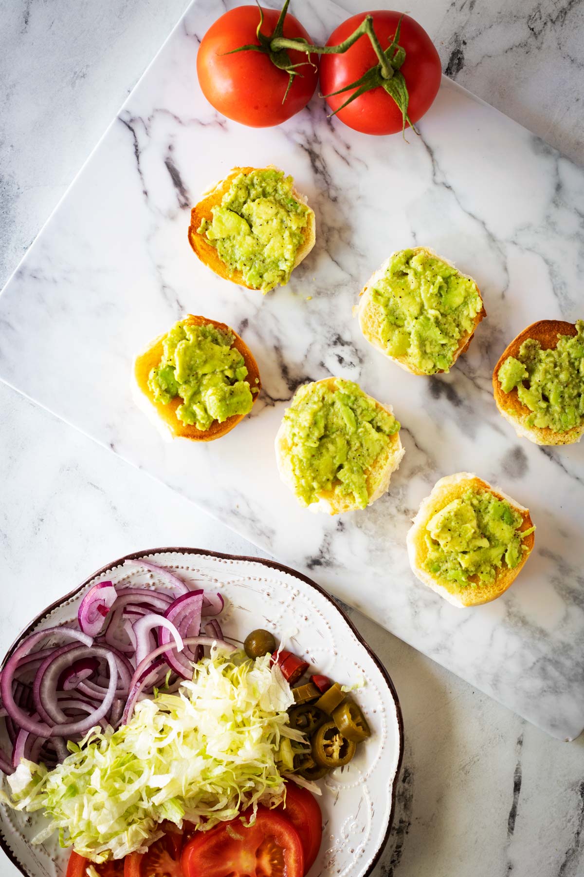 Slider buns topped with mashed avocado.