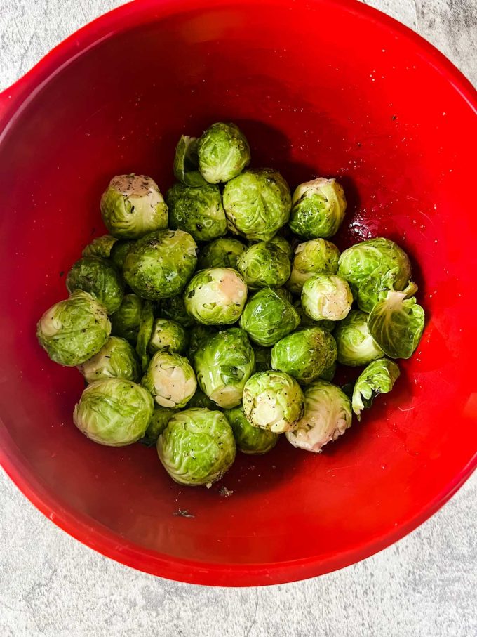 Photo of seasoned Brussels Sprouts in a red bowl.