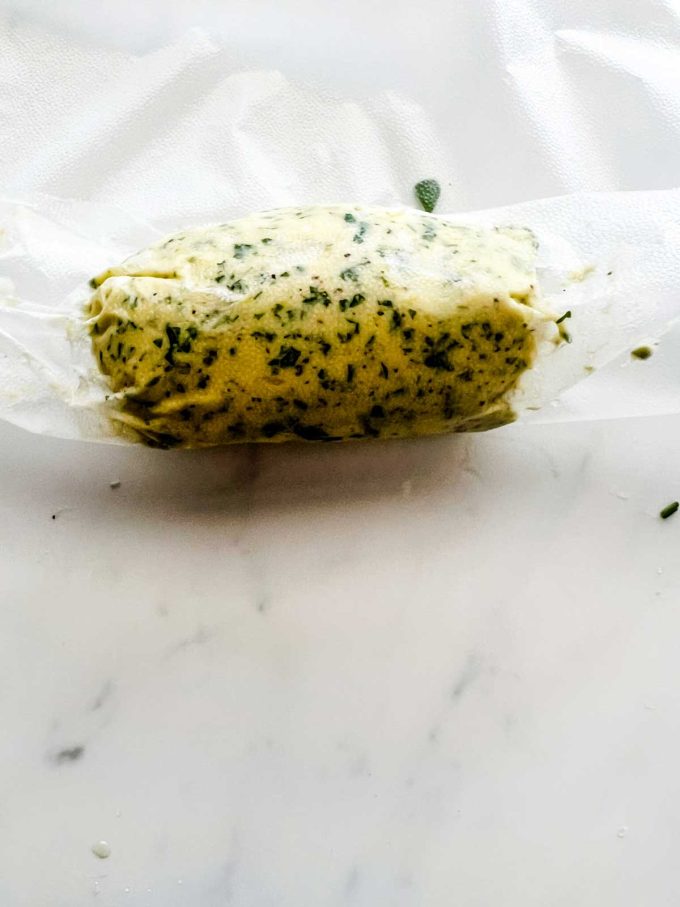 Photo of compound butter being rolled into plastic wrap.