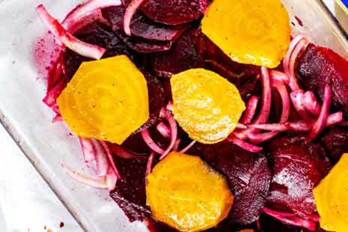 Beets and onions in a baking dish with orange salad dressing.