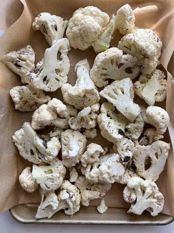 Photo of seasoned cauliflower on a parchment lined sheet pan.