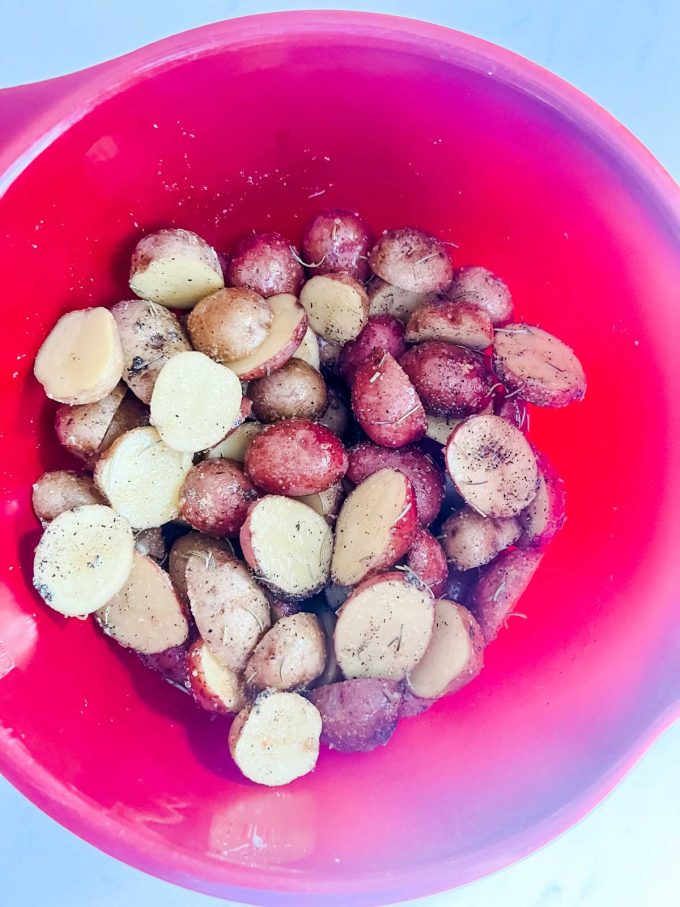 Photo of a red bowl with seasoned baby potatoes.