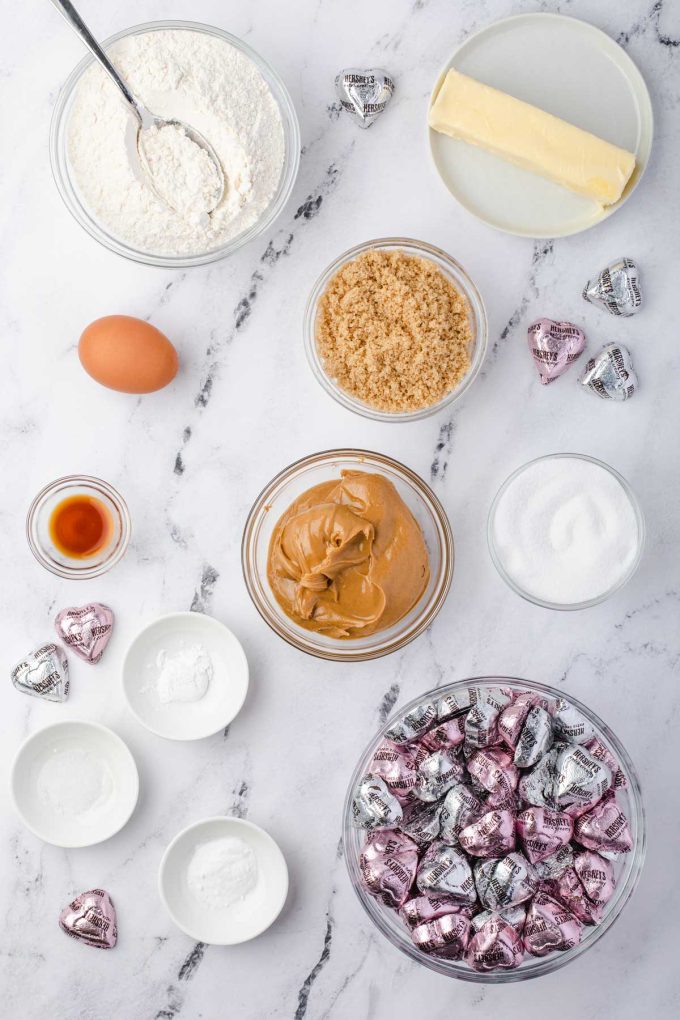 Overheat photo of flour, butter, brown sugar, sugar, peanut butter, an egg, vanilla, salt, baking soda, and baking powder in prep bowls.