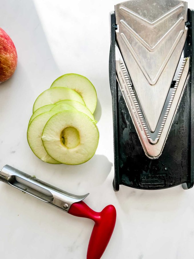 Photo of an apple corer, a mandoline, and cored apple slices.