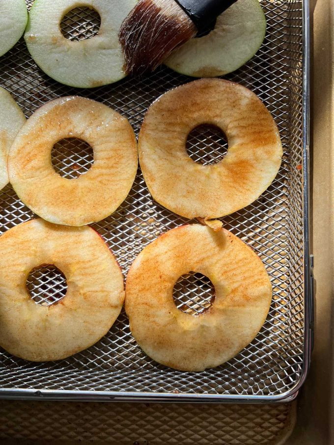 Overhead Photo of apple slices that have been brushed with seasoning in an air fryer basket.