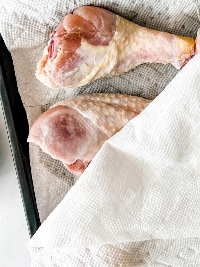 Photo of chicken legs being dried with paper towels.