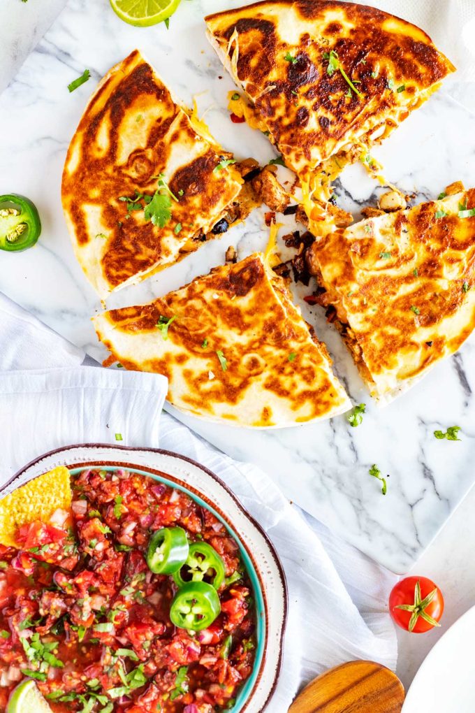 Photo of chicken quesadillas sitting next to a bowl salsa.