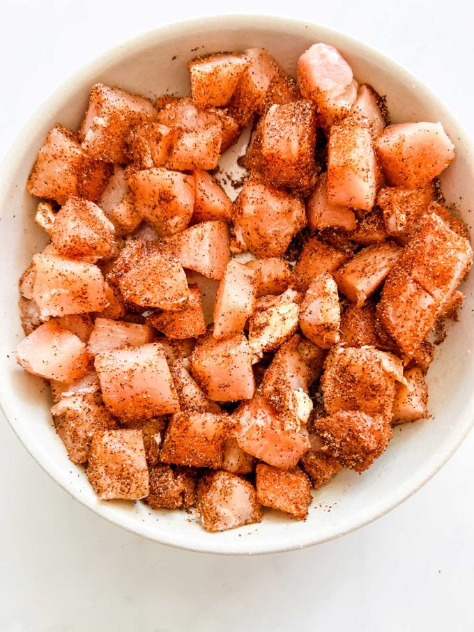 Photo of chicken tossed with taco seasoning in a white bowl.