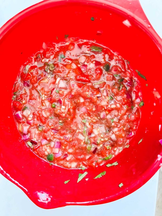 Photo of onion, tomatoes, chipotle chiles, jalapeno, garlic, lime, cilantro, salt and pepper in a large bowl.