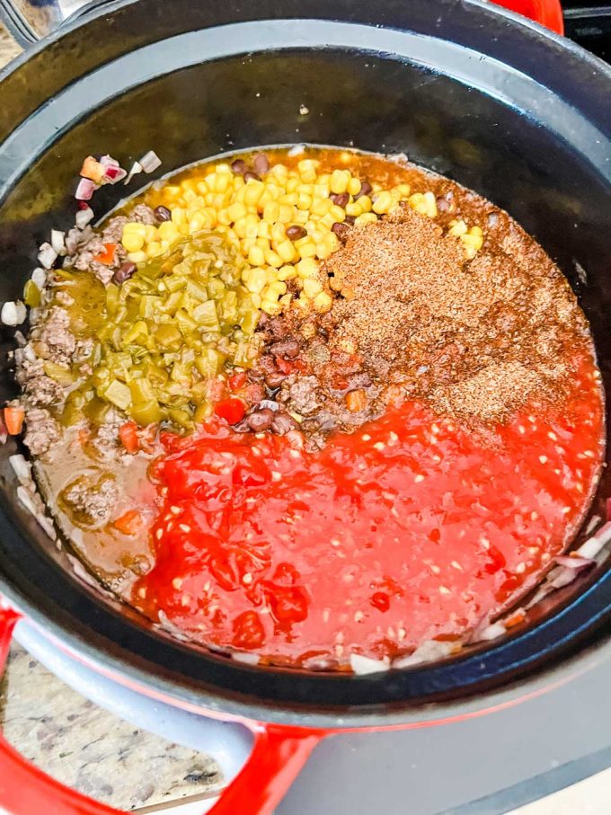 Photo of mild green chilies, pureed tomato, corn, and black beans being added to slow cooker taco soup.