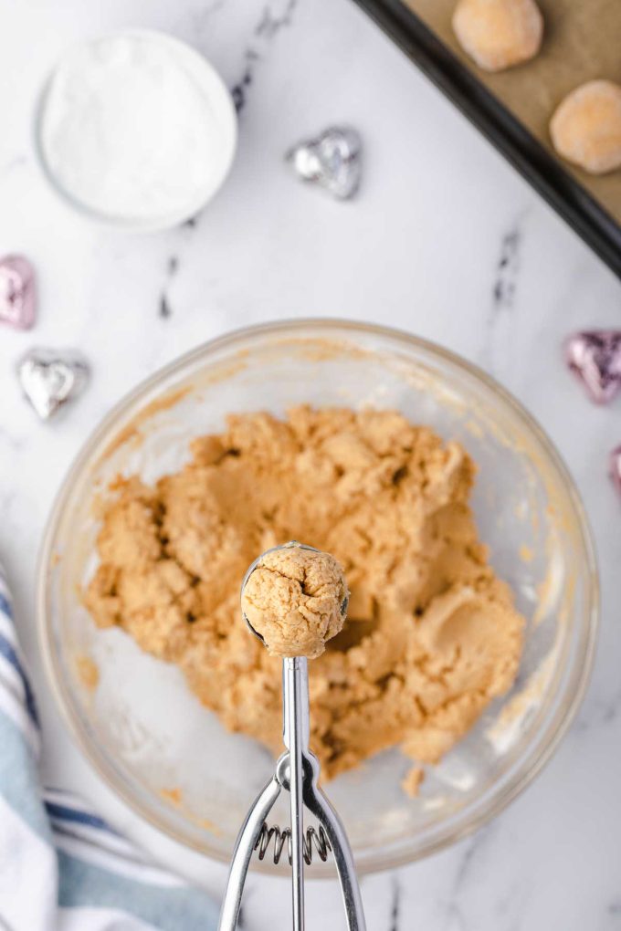 Photo of a cookie scoop that has just scooped up cookie dough from a bowl.