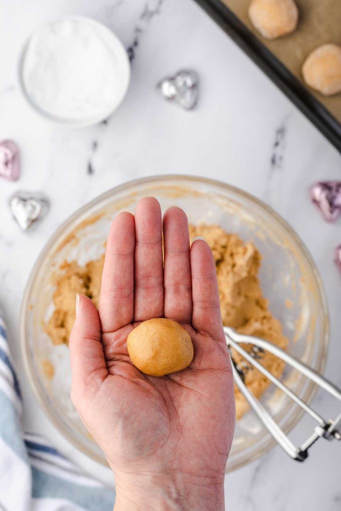 Photo of a peanut butter cookie being formed into a ball.