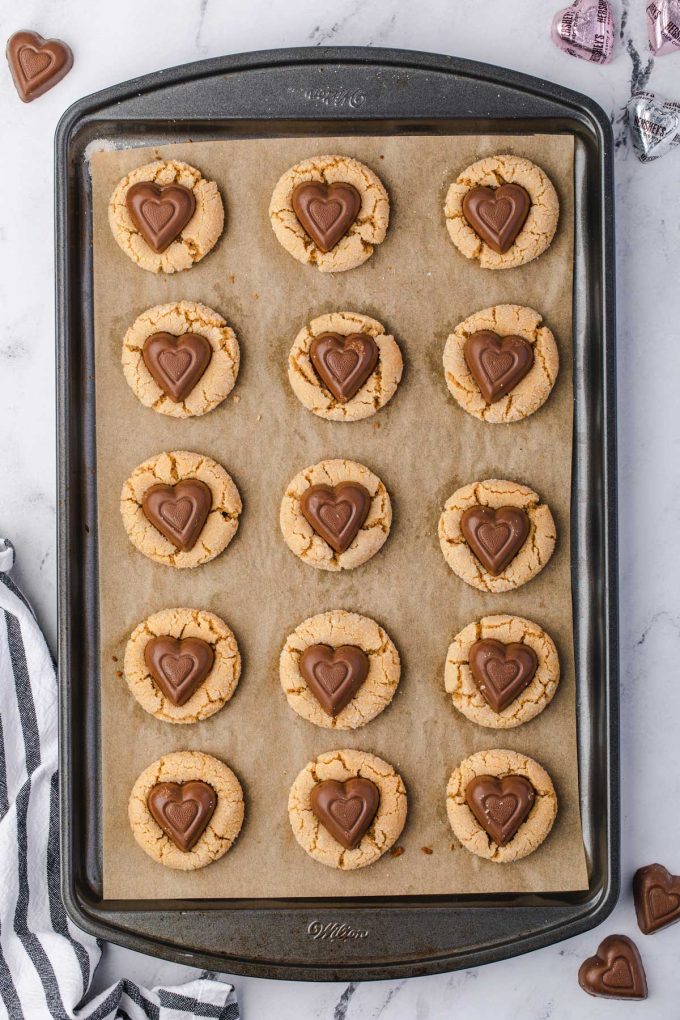 Photo of peanut butter blossoms on a parchment lined baking sheet.