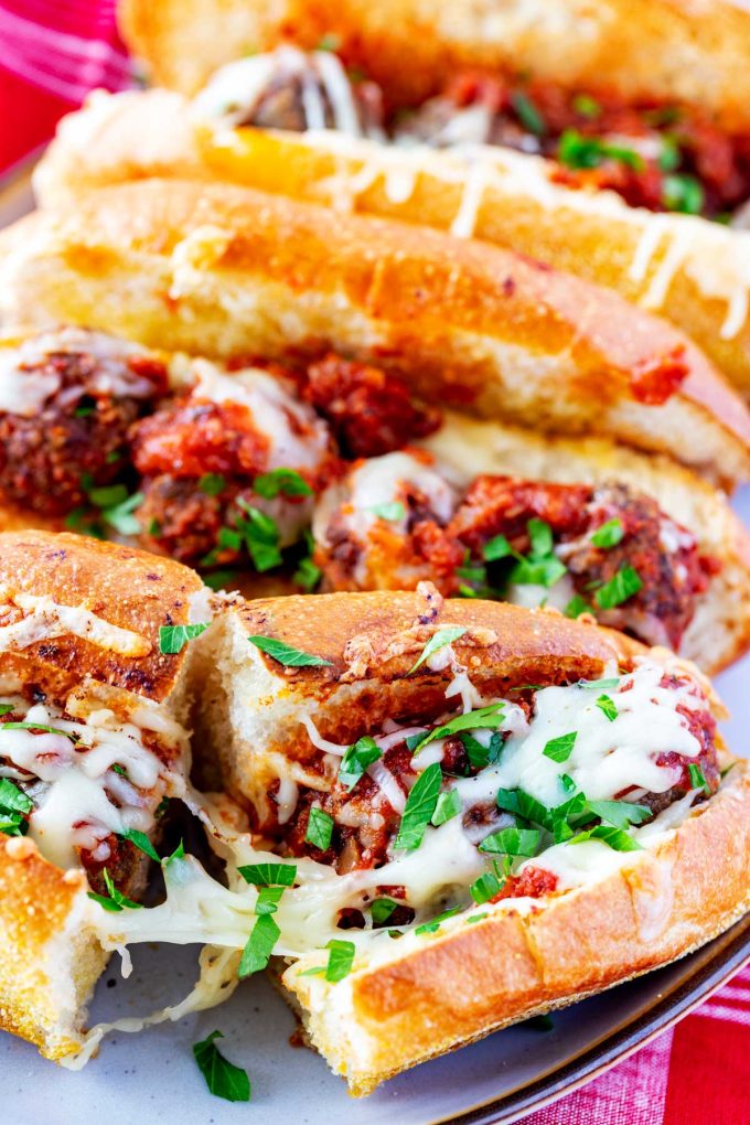 Photo of a meatball sub cut in half with a cheese pull.