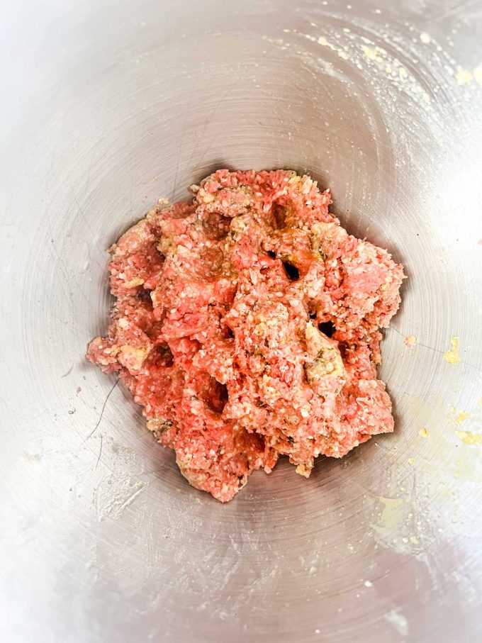 Photo of the mixture for meatballs mixed together in a metal bowl.