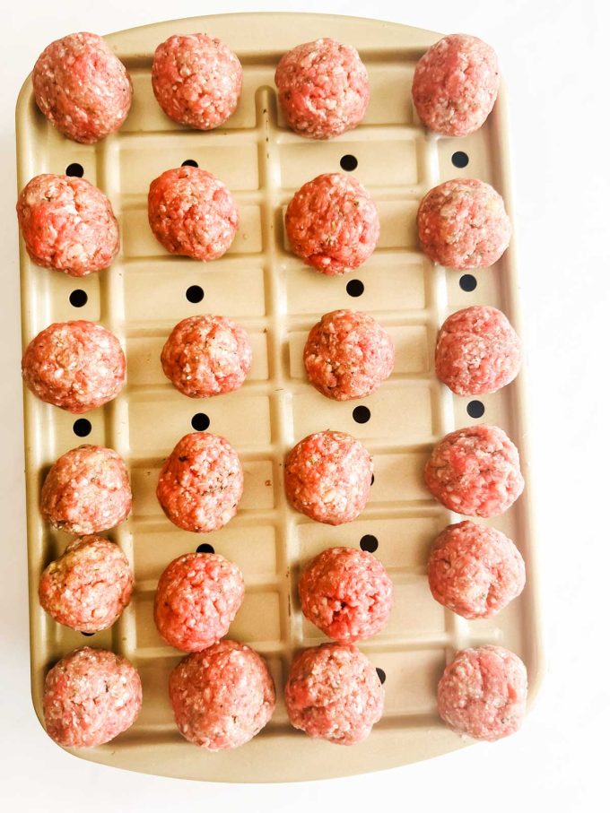 Photo of meatballs on a baking pan with holes so the grease can drip below.