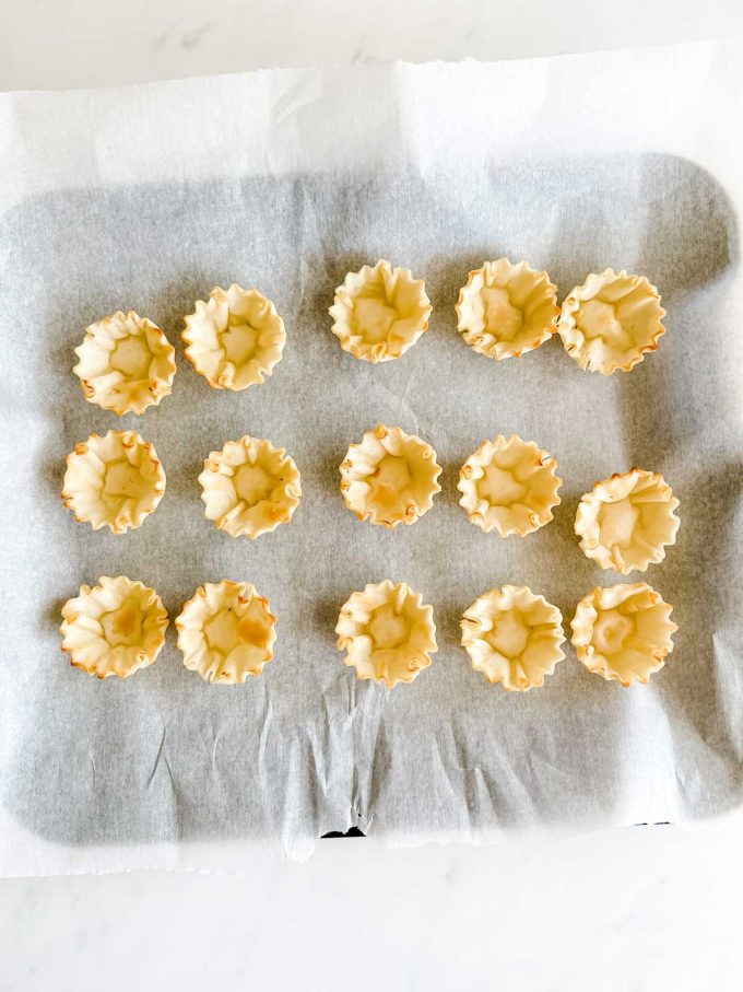 Photo of phyllo shells on a parchment lined baking sheet.