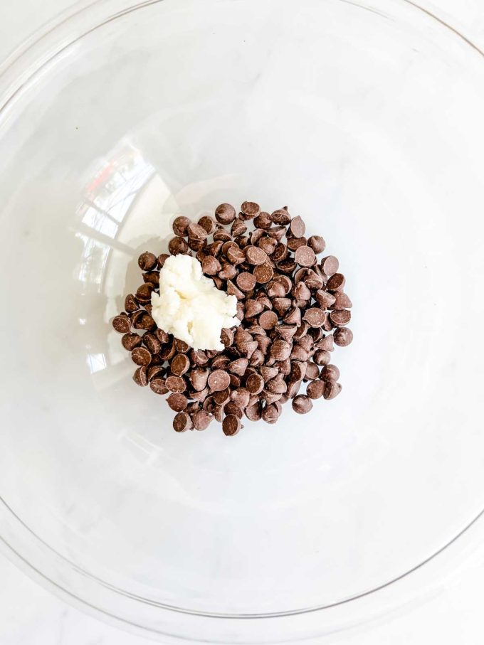 Photo of chocolate chips and coconut oil in a small glass bowl.