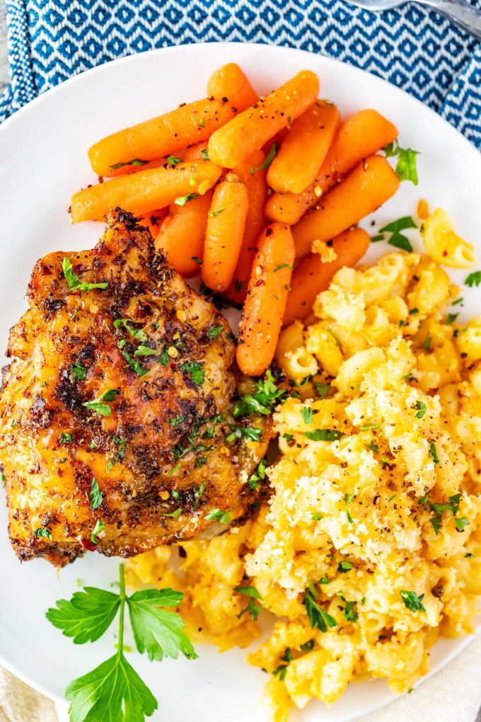 Photo of Baked Macaroni and cheese plated with chicken thighs and baby carrots.