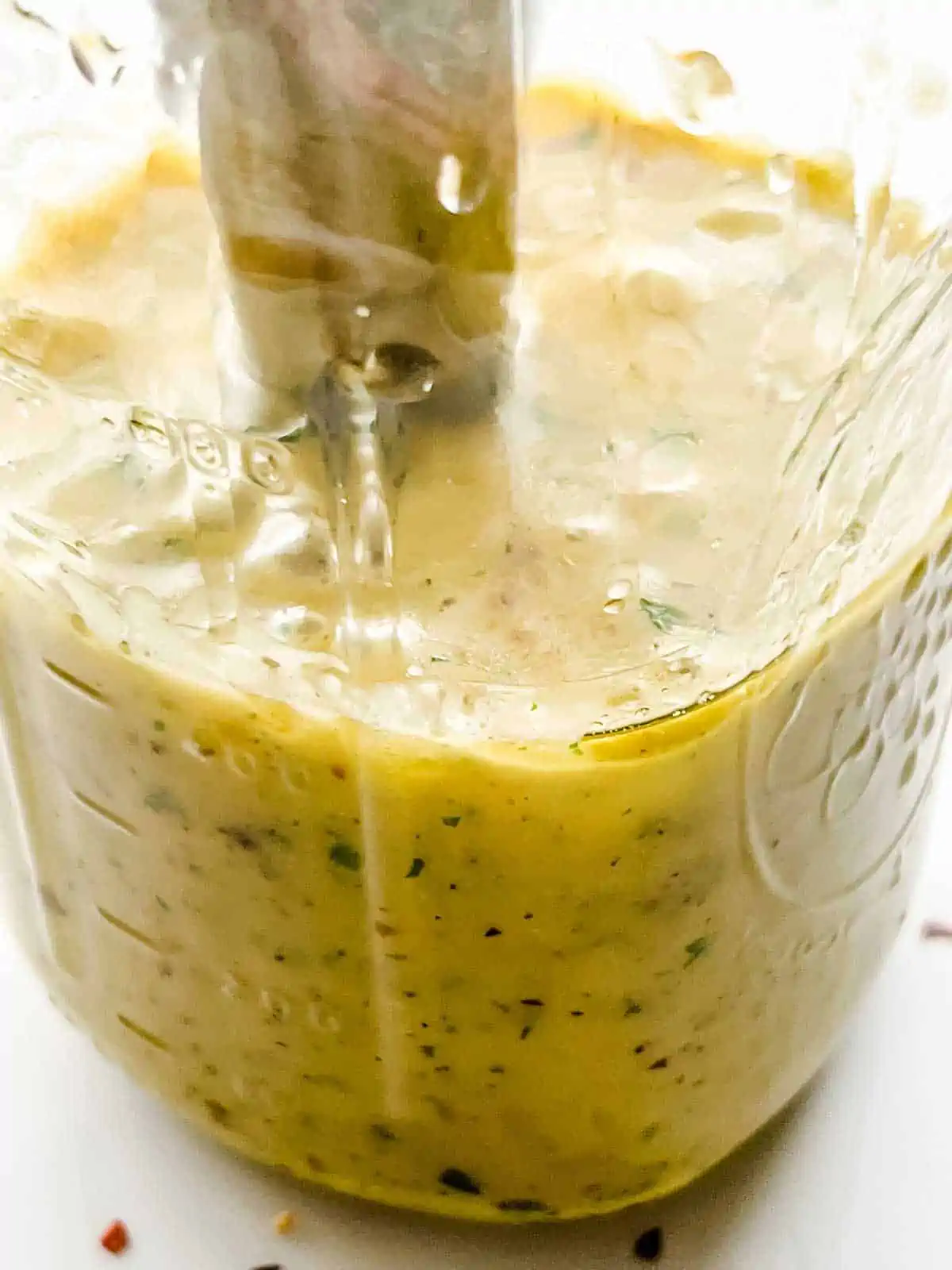 Close up photo of Italian Dressing in a mason jar being blended with an immersion blender.