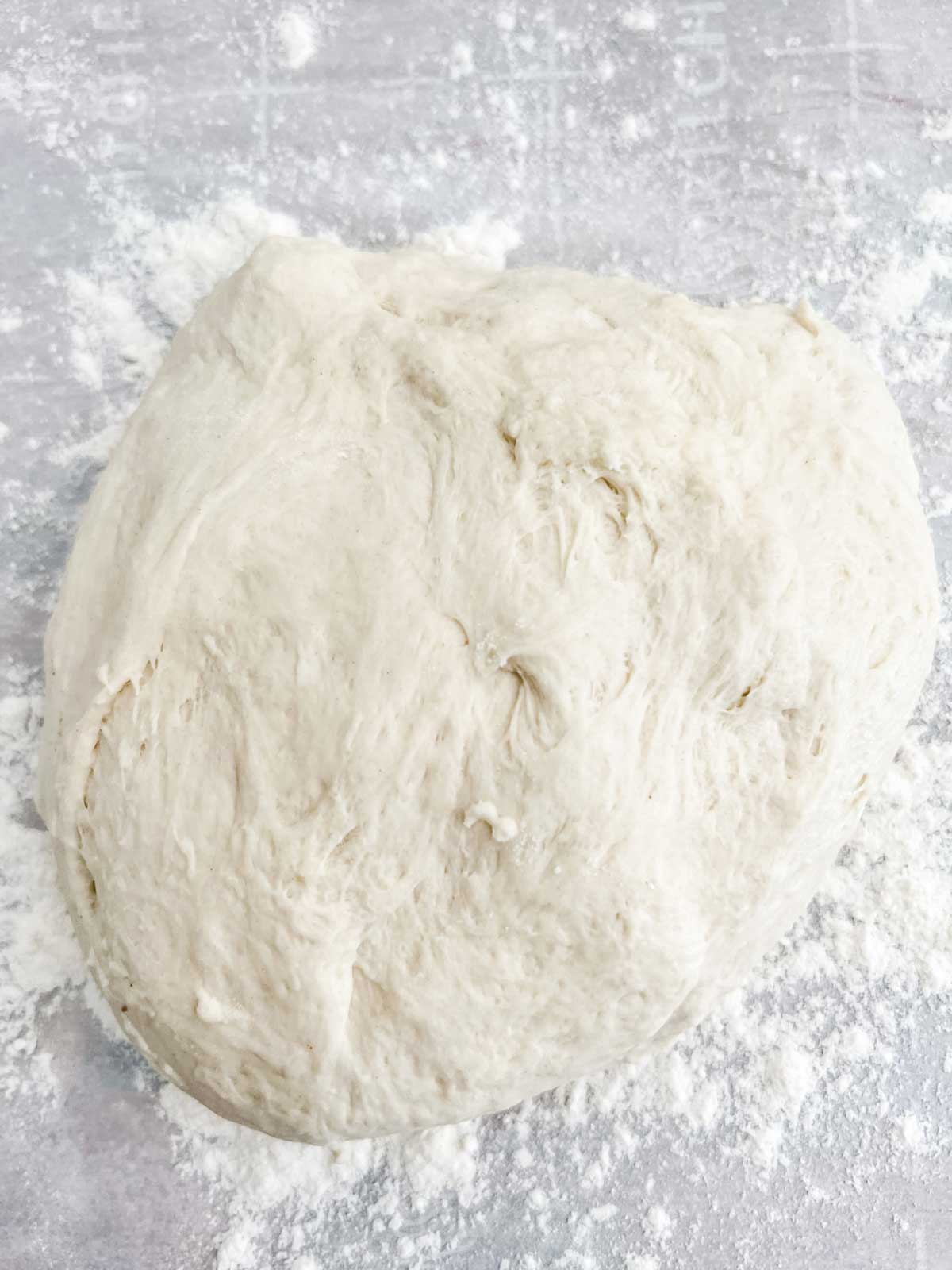 Photo of a pizza dough on a flour lined piece of parchment paper.