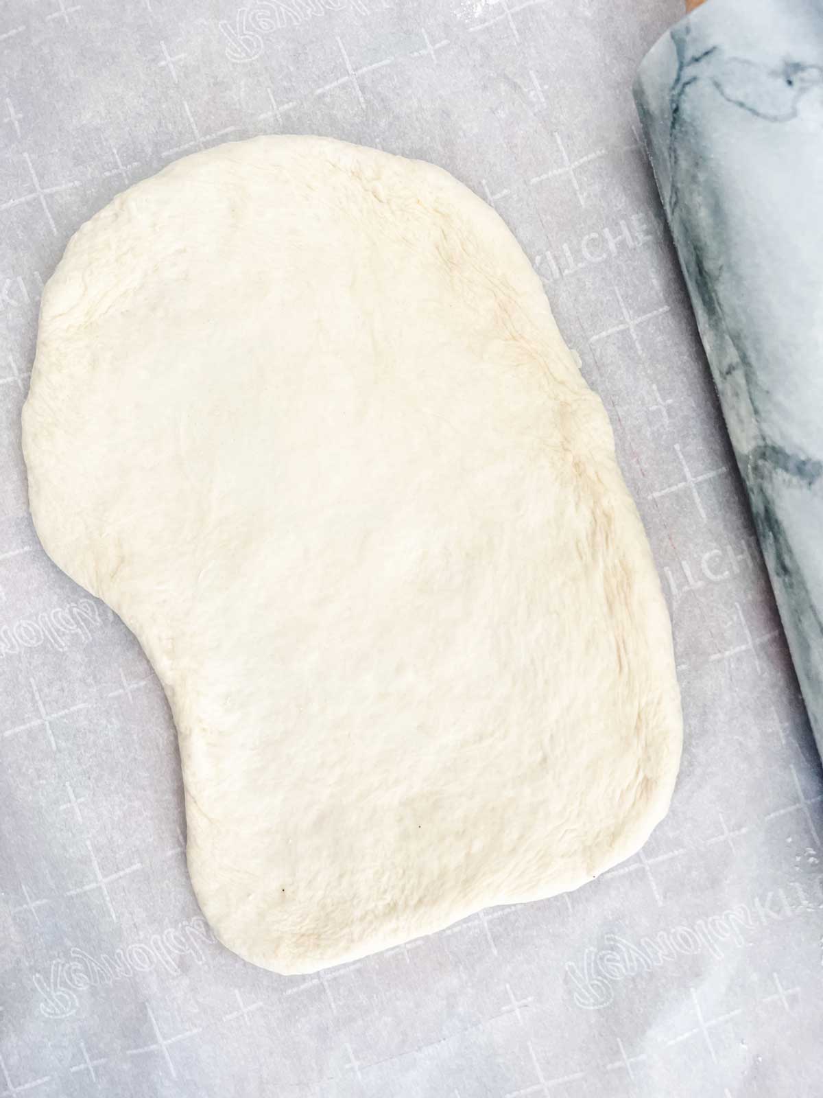 Rustic shaped pizza dough that has been rolled out.