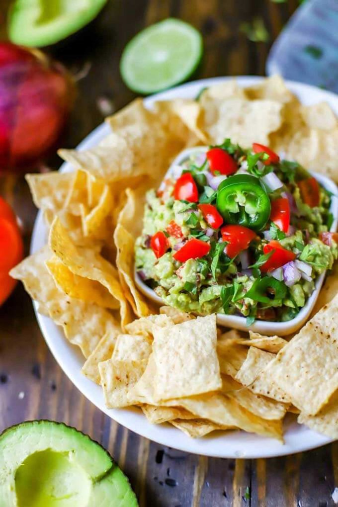 Photo of a small bowl of bacon guacamole surrounded by tortilla chips.