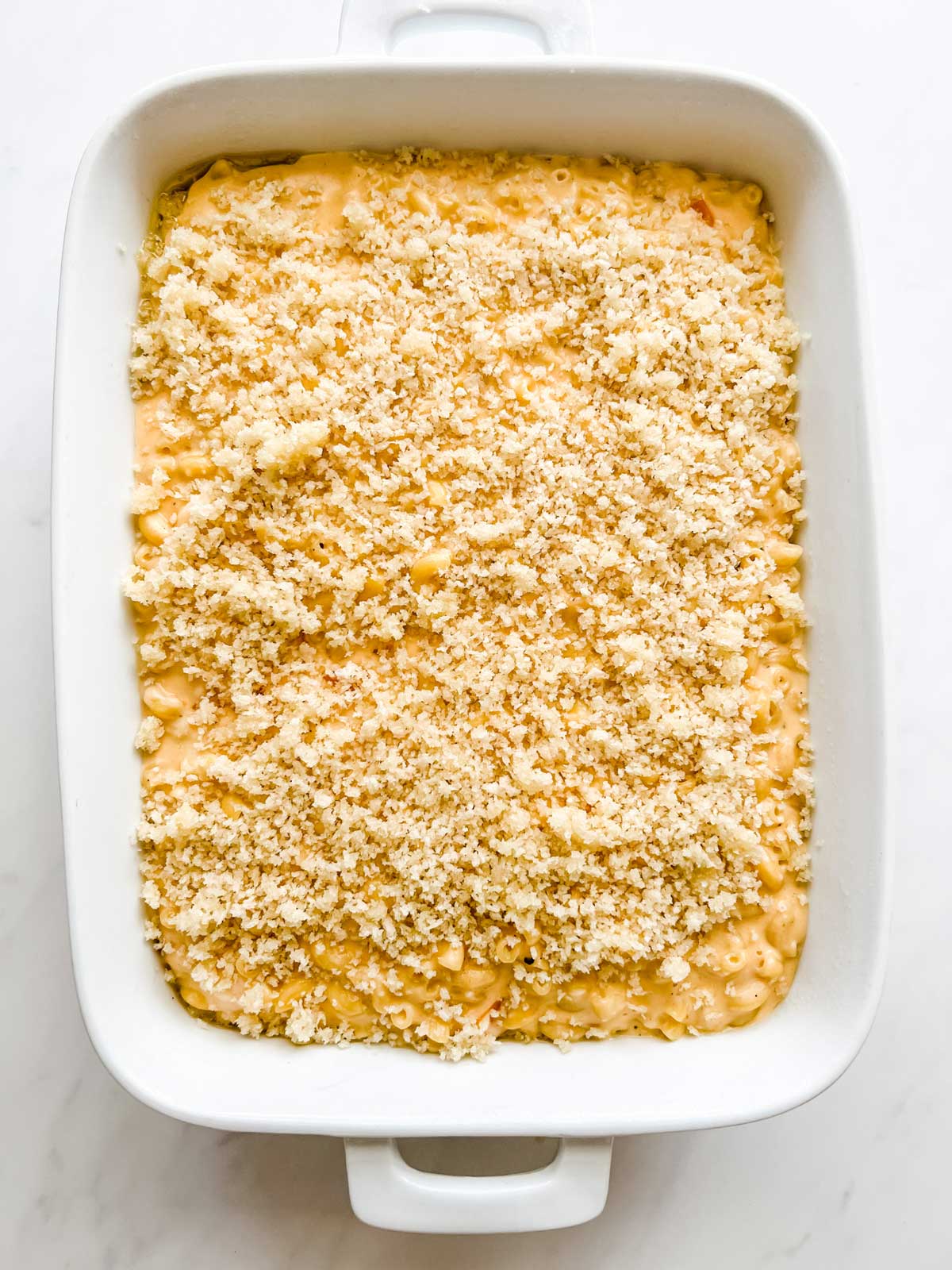 Macaroni and cheese with breadcrumbs on top in a casserole dish.
