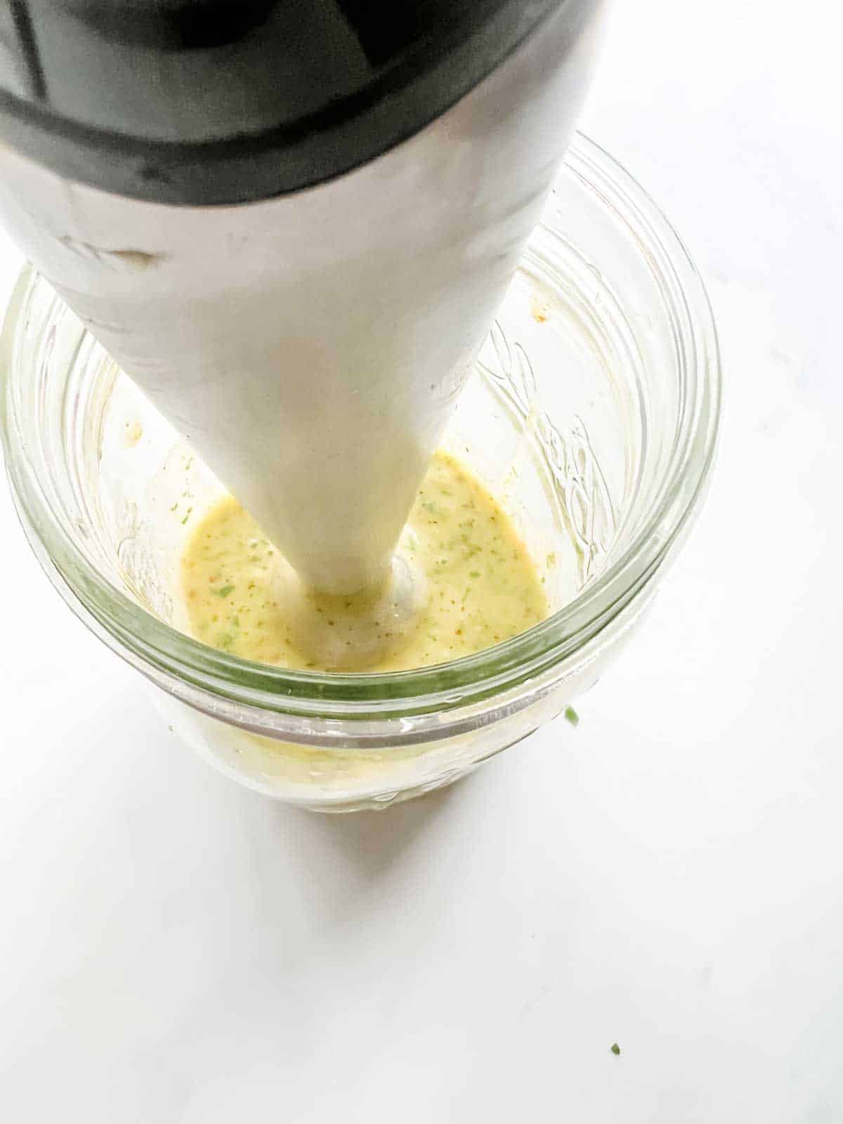 Salad dressing being blended with an immersion blender.