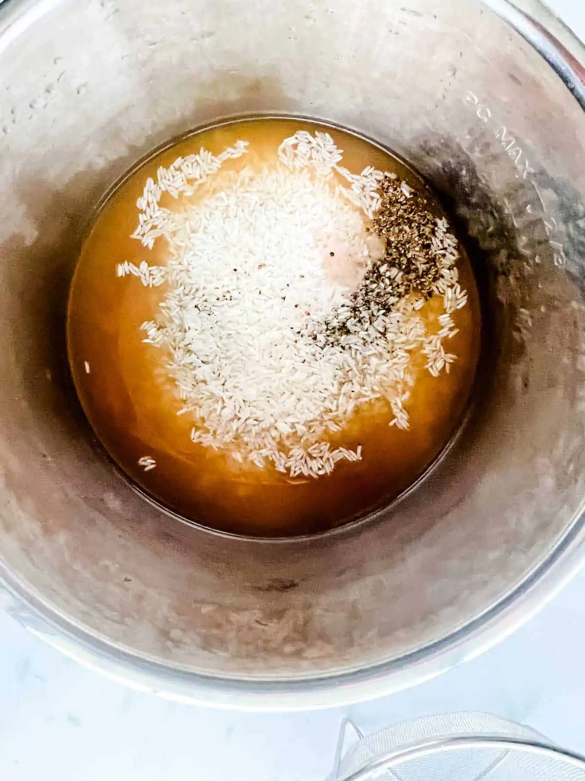 Broth, rice, and seasonings in an Instant Pot.
