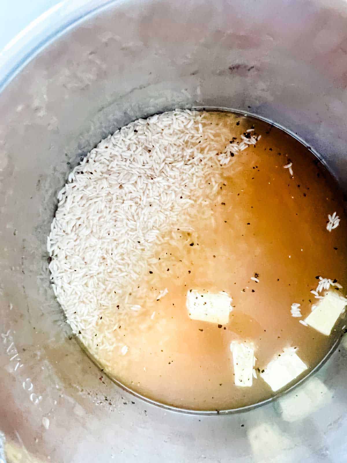Broth, rice, seasonings, and butter in an Instant Pot.