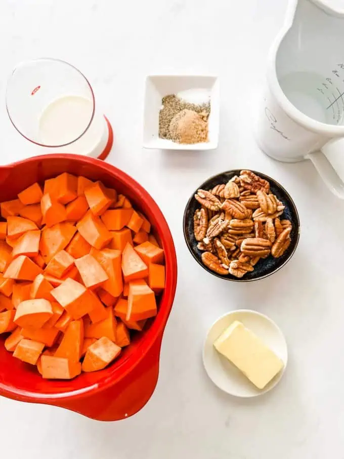 Overhead photo of cubed sweet potatoes, cream, seasonings, water, butter, and pecans in prep containers.