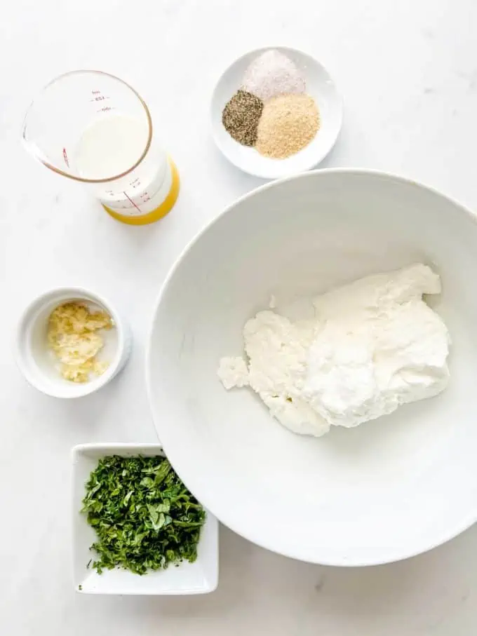 Overhead photo of Greek yogurt, buttermilk, garlic, parsley, and seasonings in prep containers.