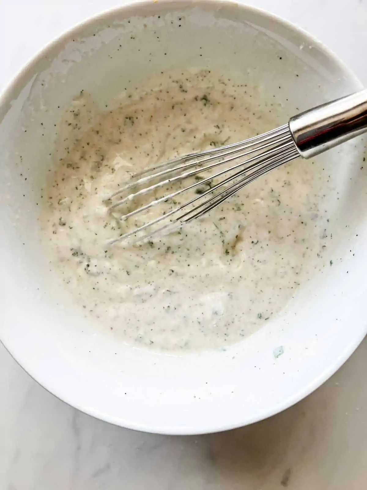 Greek yogurt ranch dressing being whisked together in a bowl.