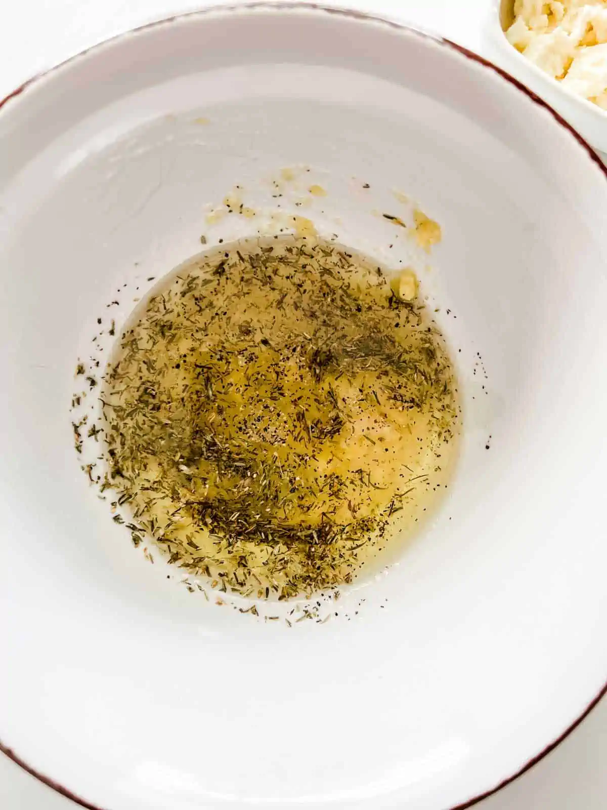 Photo of oil, garlic and seasonings in a small bowl.