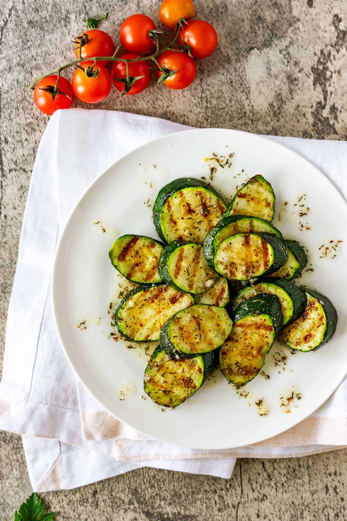 Photo of grilled zucchini on a plate drizzled with dressing.
