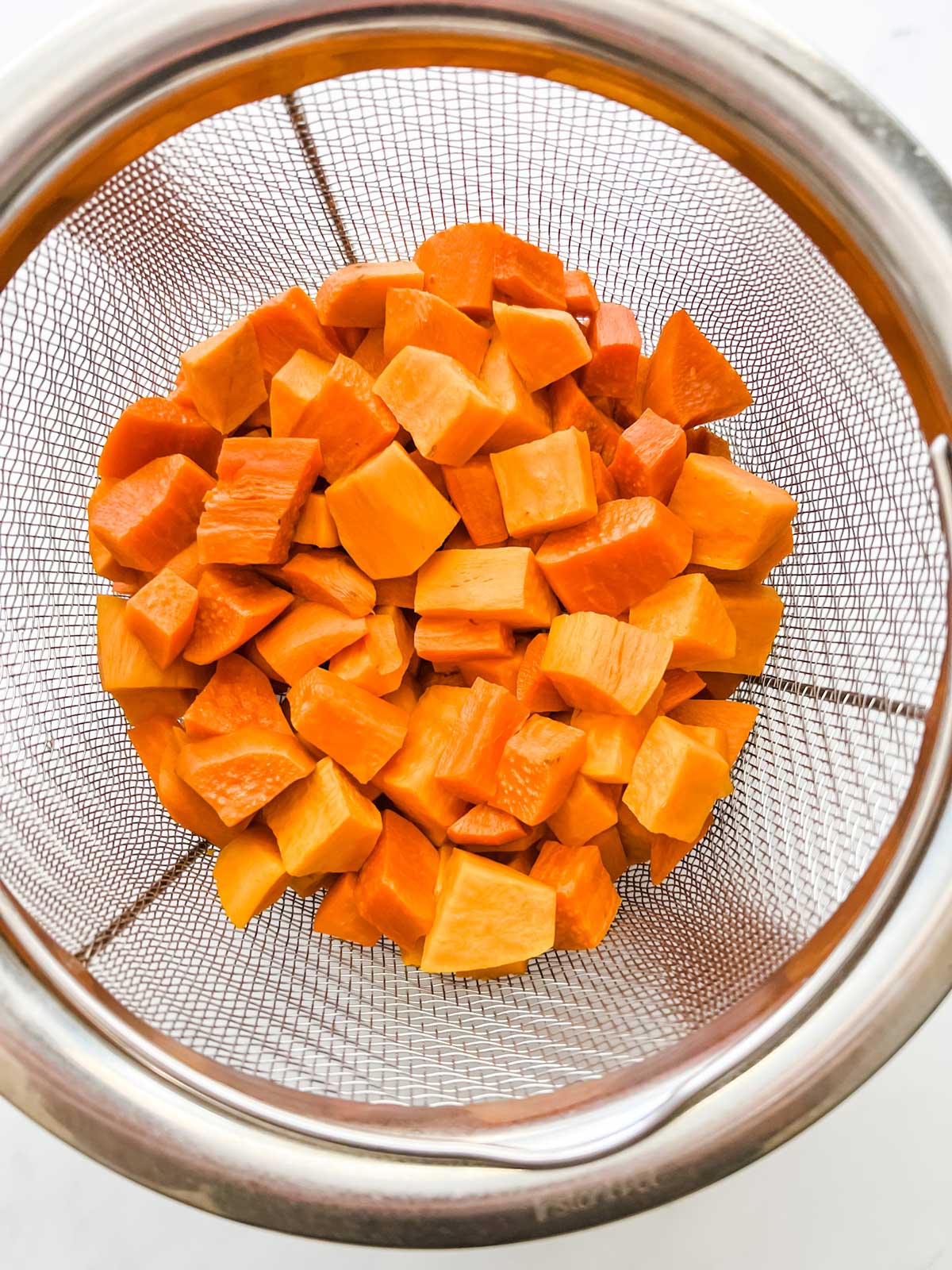 Cubed sweet potatoes in a steamer basket that have been cooked in an Instant Pot.