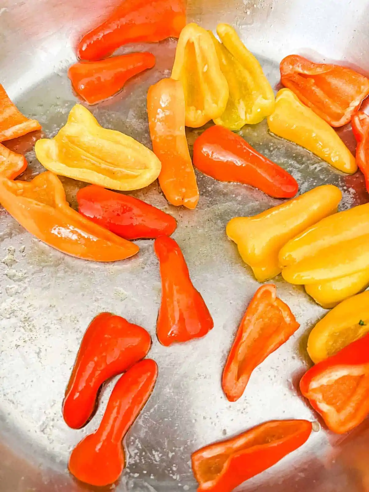Baby peppers being sautéed in a skillet.