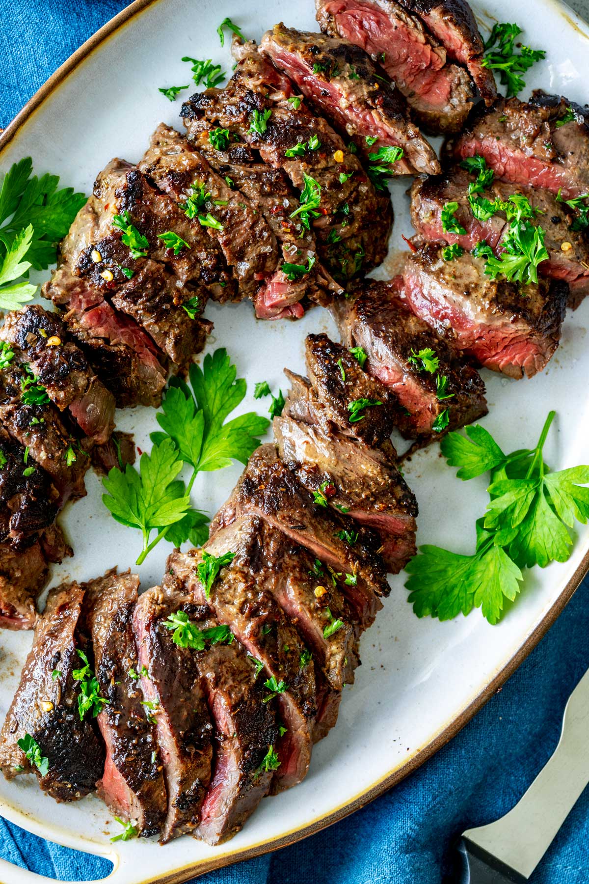 Close up photo of a hanger steak recipe on a platter garnished with parsley.