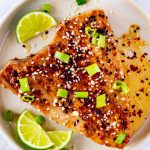 Overhead photo of an air fryer tuna steak topped with a sweet heat sauce and garnished with sesame seeds and green onions.
