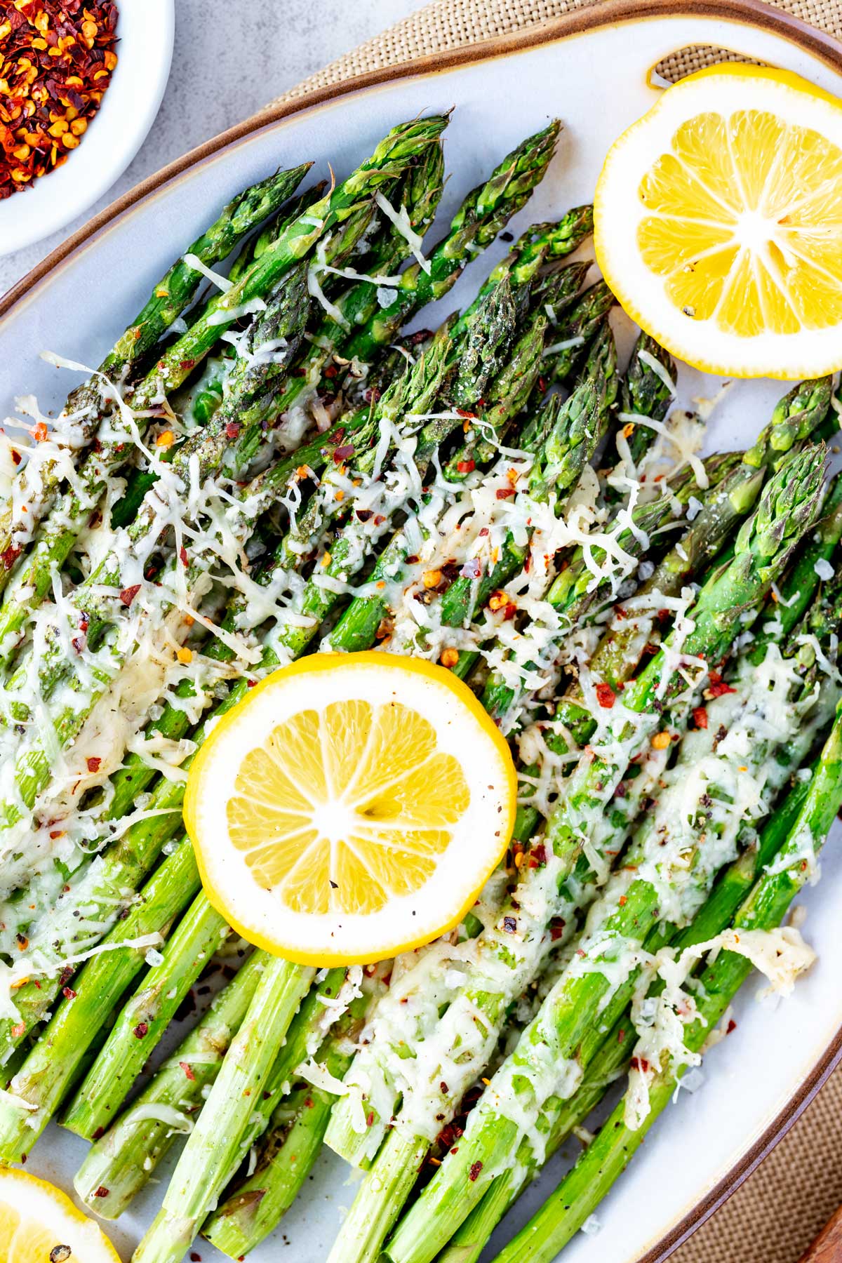 Close up overhead photo of Baked Asparagus on a platter with lemons.