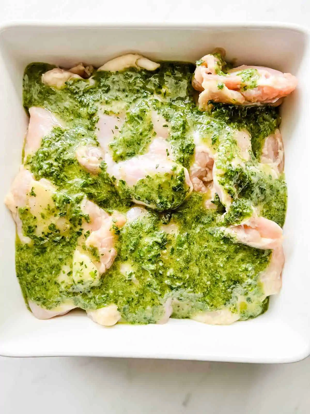 Photo of chicken thighs marinating in a casserole dish.