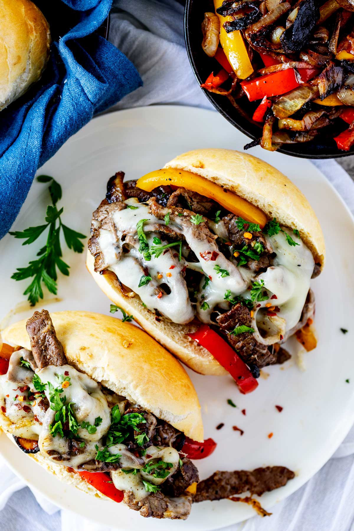 Overhead photo of a Blackstone Philly Cheesesteak on a white plate garnished with parsley.