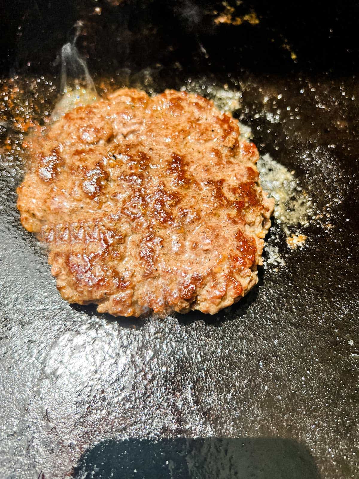 Photo of a smash burger cooking on a Blackstone griddle.