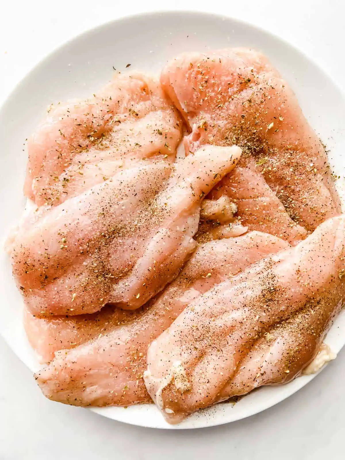 Photo of raw chicken that has been seasoned.